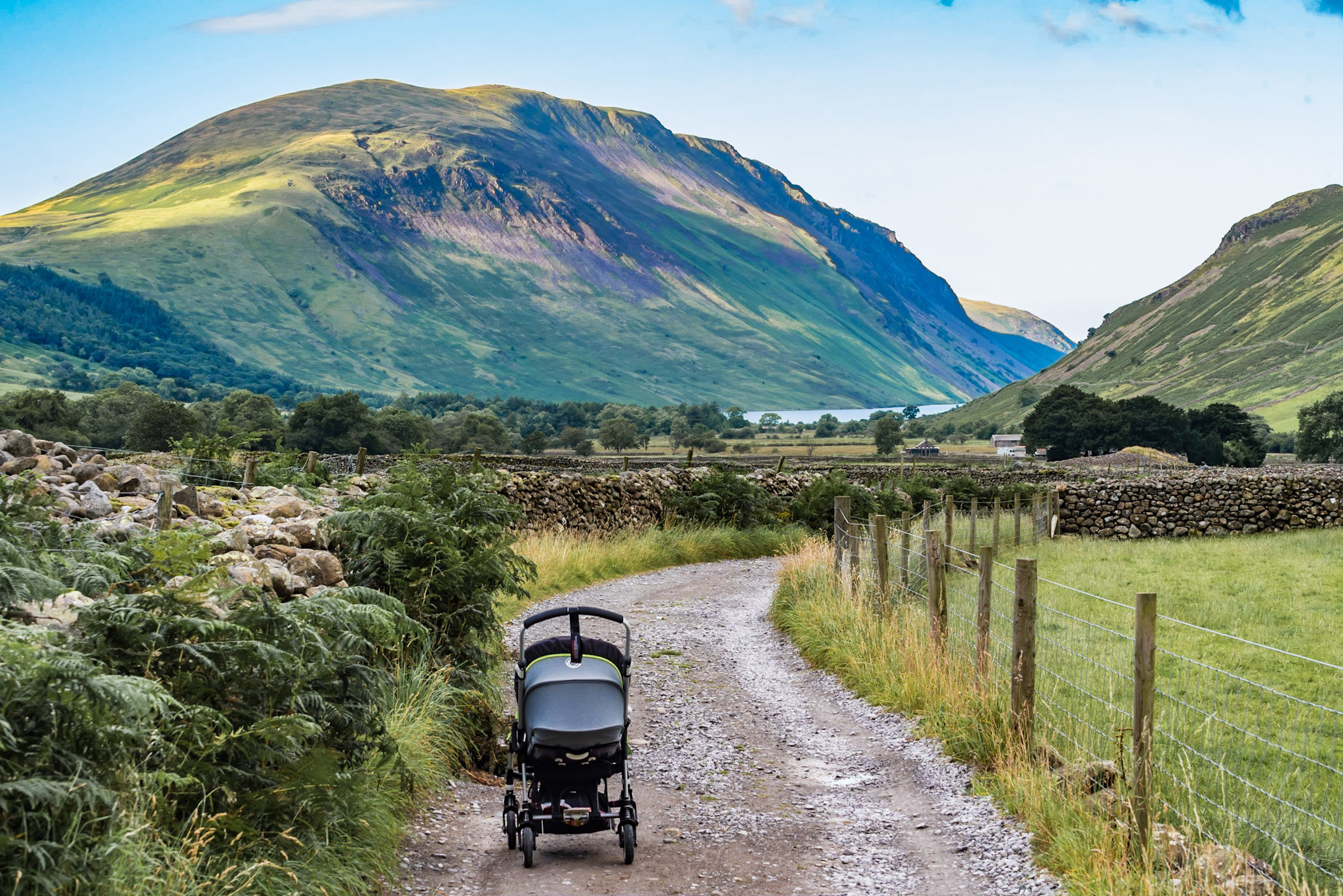 A pushchair with a sleeping baby in it on a country road in the mountains