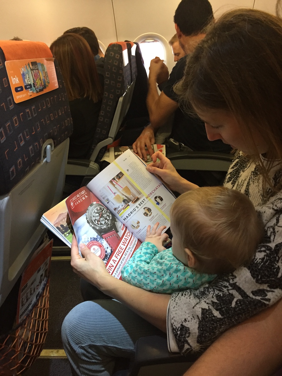 A mother and child look at a magazine on a plane