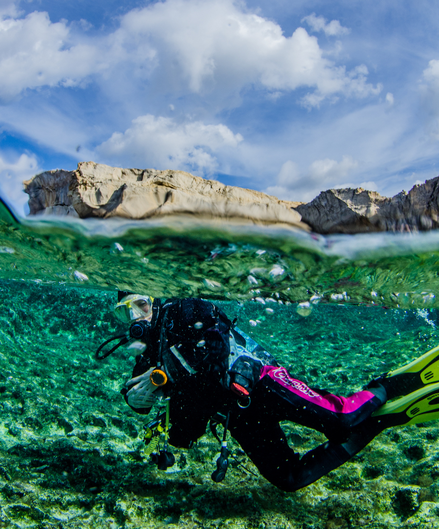 A scuba diver in shallow water, with Crocodile Rock in the background