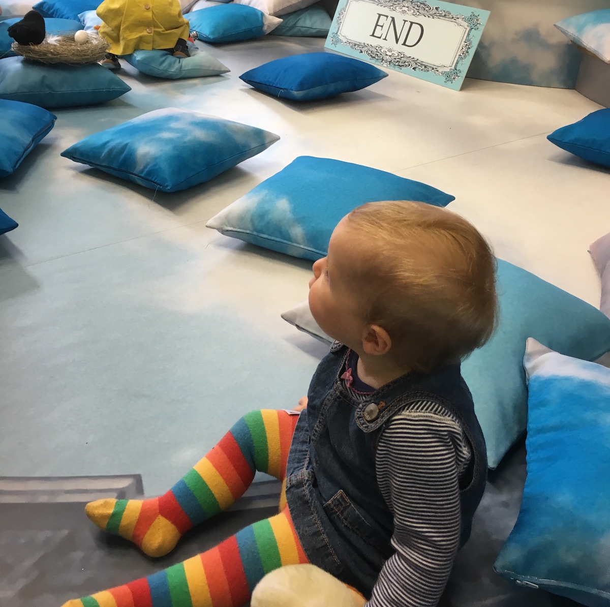 A baby girl sits on stage at the end of a performance for babies