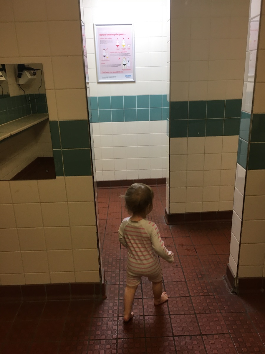 A toddler in a swimming pool changing room