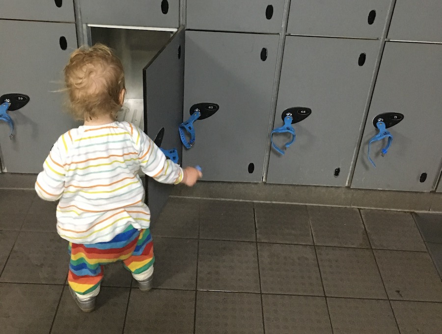 A toddler looks into a locker