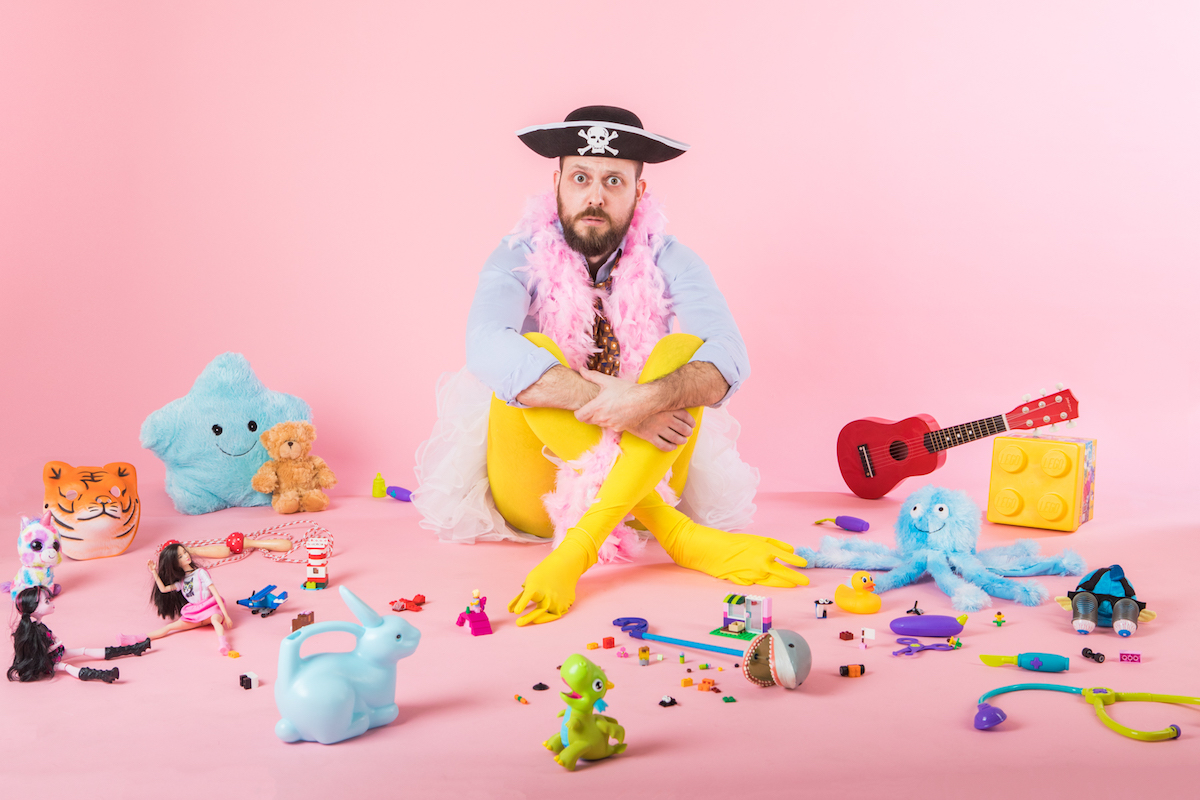 Comedian Owen Roberts wears silly clothes, surrounded by toys in a pink room, advertising his new show at the Edinburgh Festival Fringe © Ben Carpenter